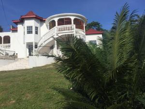 a white house with a palm tree in front of it at Jannetta's @Whimhill Bed & Breakfast in Negril