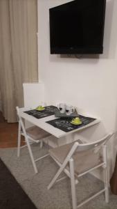 a white table with a stove and a tv on a wall at Il CASALETTO di Laura in Fiumicino