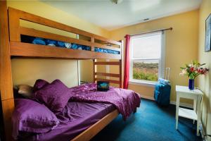 een slaapkamer met een stapelbed met paarse lakens en een raam bij HI Pigeon Point Lighthouse Hostel in Pescadero
