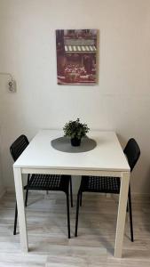 uma mesa branca com duas cadeiras e um vaso de plantas sobre ela em Kallion helmi em Helsinque