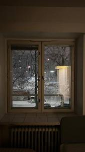 una finestra in una stanza che si affaccia su un cortile coperto di neve di Kallion helmi a Helsinki