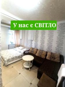 Dormitorio con sofá, cama y cartel en Готель Жасмин en Ternopilʼ