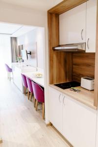 une cuisine avec des armoires blanches et des chaises violettes dans l'établissement Appartements Am Kranichsee, à Hahnenklee