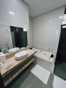 a bathroom with a sink and a tub and a toilet at Hotel Esmeralda Verde in Teófilo Otoni