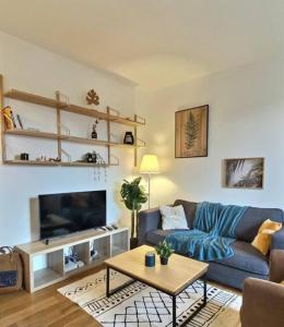 sala de estar con sofá azul y mesa en Appartement 2 pièces à quelques minutes de Paris en Le Pré-Saint-Gervais