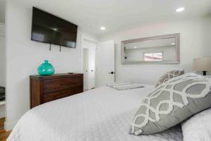 1 dormitorio con 1 cama blanca y TV en la pared en Sleeps 16 - 15 min/Downtown, 10 min/Medical Center en Aurora