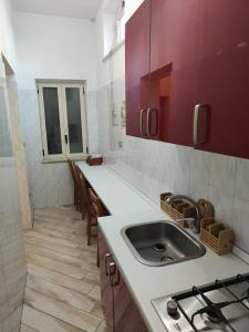 a kitchen with a sink and red cabinets at Oikos in Boscotrecase