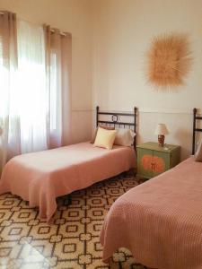 a bedroom with two beds and a window and a table at Casa Miraflores in Seville