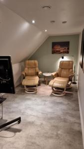 uma sala de estar com duas cadeiras e uma mesa em Værelse, spiseområde, tv-stue og eget bad på landet em Kværndrup