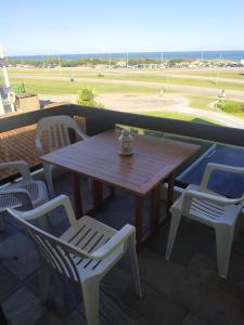 una mesa de madera y sillas en un balcón con vistas a un campo en Frente a playa brava, en Punta del Este