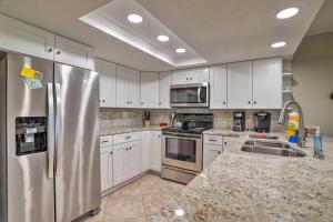 a kitchen with white cabinets and a stainless steel refrigerator at Indian Shores Condo with 2 Balconies and Pool Access! in Clearwater Beach