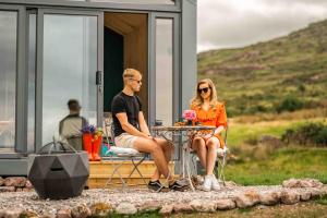 a man and woman sitting at a table outside of a house at Oaklane Glamping Cabins in Kenmare