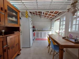 cocina con mesa y nevera blanca en Casa decorada perto da Praia de Perequê - Ilhabela, en Ilhabela