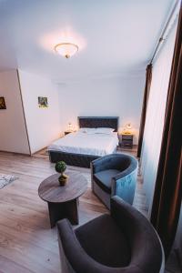 a bedroom with a bed and two chairs and a table at Motel Piatra Corbului in Bicaz