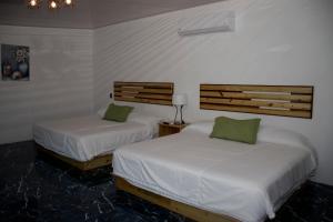 2 Betten in einem Zimmer mit weißer Bettwäsche und grünen Kissen in der Unterkunft Hotel Samoa del Sur in Golfito