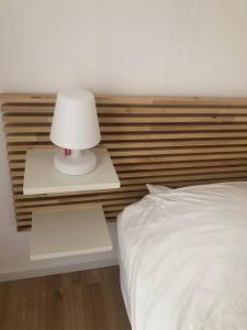 łóżko z białą lampką na stoliku nocnym obok łóżka w obiekcie Maison La teste de Buch 3 chambres w mieście La Teste-de-Buch