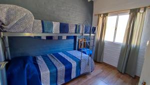 ein Schlafzimmer mit einem Etagenbett mit blauen und weißen Streifen in der Unterkunft Cabañas Laureano AJ in Cacheuta