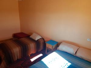 a small room with two beds and a table at Chez Meriem in Merzouga
