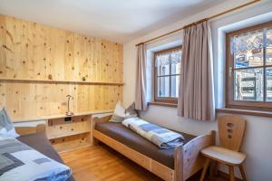 a bedroom with a bed and two windows at Kalchgruberhof Wohnung Enzian in Ultimo