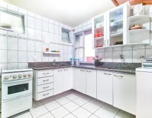 a kitchen with white cabinets and white appliances at Estada Inesquecível 03 Guarapari/Peracanga Bacutia in Guarapari