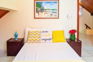 a bedroom with a white bed with colorful pillows at Estada Inesquecível 03 Guarapari/Peracanga Bacutia in Guarapari