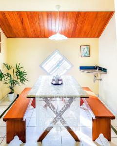 a dining room with a glass table and benches at Estada Inesquecível 03 Guarapari/Peracanga Bacutia in Guarapari