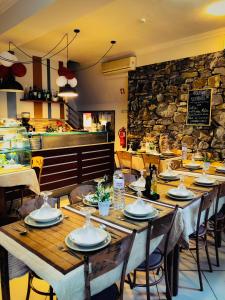 comedor con mesas y sillas y pared de piedra en Abrigo da Estrela, en Covilhã