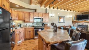 a kitchen with wooden cabinets and a table and a couch at Forest Lane Hideaway - Luxurious Family Friendly Home with Private Hot Tub in Big White