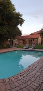 a swimming pool with blue water in front of a house at Sha-Mani Guesthouse & Conference Venue in Alberton