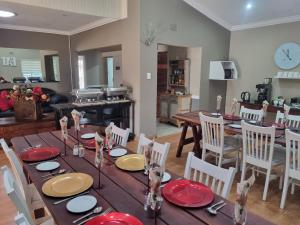 ein Esszimmer und ein Wohnzimmer mit einem Tisch mit roten Platten in der Unterkunft Sha-Mani Guesthouse & Conference Venue in Alberton
