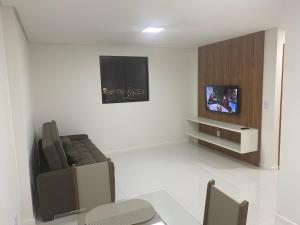 sala de estar con sofá y TV en la pared en Vista Mar com 2 quartos, en Maceió