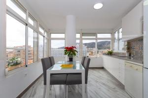 a white kitchen with a table and chairs and windows at Apt Playa y Montaña in Torremolinos