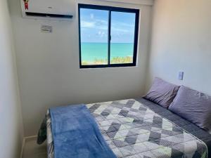 1 dormitorio con vistas al océano desde una ventana en Vista Mar com 2 quartos, en Maceió