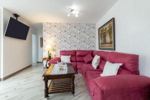 a living room with a red couch and a table at Apt Playa y Montaña in Torremolinos