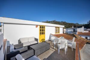 eine Terrasse mit Stühlen, Tischen und einer gelben Tür in der Unterkunft Apartamento Amarelo in Odeceixe