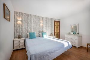 a bedroom with a large white bed with blue pillows at Apartamento Amarelo in Odeceixe