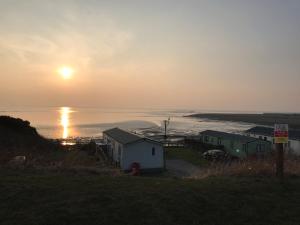 a sunset over the ocean with houses on a hill at Bobbys Bolthole2 in Heysham