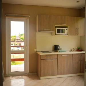 a kitchen with wooden cabinets and a microwave and a window at Apartments Izumrudniy Bereg in Gudauta