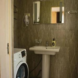 a bathroom with a sink and a washing machine at Apartments Izumrudniy Bereg in Gudauta