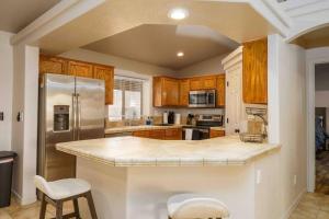 a kitchen with wooden cabinets and a stainless steel refrigerator at Havasu lake house 4 BR & 3 BA w/pool & hot tub in Lake Havasu City