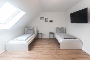 two beds in a room with a tv on the wall at Eindrucksvolles Gruppen– und Monteursloft in Edingen-Neckarhausen