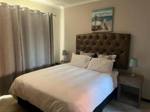a bedroom with a large bed with white sheets and pillows at Centurion: Chilled Townhouse in Centurion