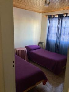 2 camas en una habitación con sábanas y cortinas púrpuras en KARUKO en Malargüe