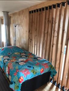 ein Schlafzimmer mit einem Bett mit einer Bettdecke darauf in der Unterkunft Cabañas Tinajas hidromasaje Chanlelfu in Puyehue