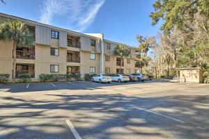 a large building with cars parked in a parking lot at Hilton Head Condo with Shared Pool - Walk to Beach! in Hilton Head Island
