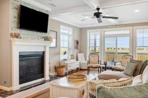 a living room with a fireplace and a flat screen tv at 616 E Erie Driftwood Marsh and River Views Private Pool in Folly Beach