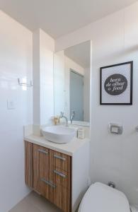 a bathroom with a sink and a toilet and a mirror at Apto Confortável e Vista Mar no Centro in Florianópolis