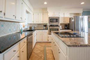 a kitchen with white cabinets and granite counter tops at Oceanfront - Decks For Days in Kure Beach