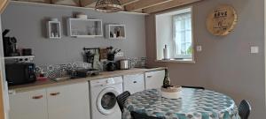 eine Küche mit einem Tisch und einer Waschmaschine in der Unterkunft Gîte - Les Pampas - Les Jardins de Kerellec - 20min de la mer - 2/4 personnes – terrasse in Plouvorn