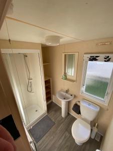 a small bathroom with a toilet and a sink at 8 Berth Holiday Home with Pools on Martello Beach in Jaywick Sands